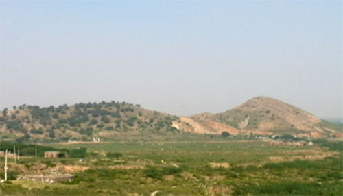 A view of two hills, one of which is barren because of mining