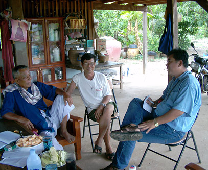 Thanawm Chuwaingan relaxes outside his home with other community leaders in Khao Din village.